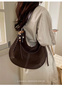 Détail du sac hobo marron foncé avec surpiqûres blanches et accessoires rétro chic