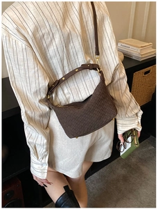 Close-up of brown woven leather hobo bag with adjustable strap and gold buckle detail