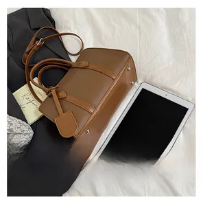 Détail du sac cabas en cuir grainé marron montrant les rivets argentés et les coutures