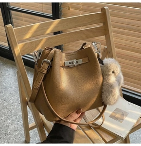 Brown litchi grain leather bucket bag with silver lock and grey plush rabbit charm