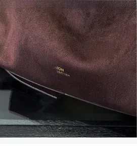 Detailaufnahme von dunkelrotem Wildleder mit goldener Prägung und feiner Textur