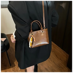 Brown vintage leather crossbody bag featuring a colorful wooden bead rock charm