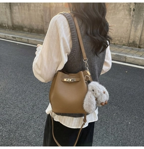 Close-up of brown bucket bag featuring lychee grain leather and a plush bunny charm