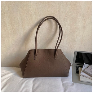 Detail of dark brown tote bag with litchi texture on a white fabric surface
