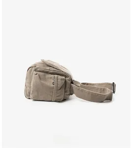 Side view of khaki canvas crossbody bag with a zippered pocket and thick woven strap