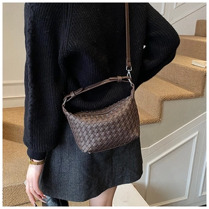 Detail of a dark brown woven leather hobo bag with adjustable strap worn by a model