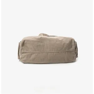 Close-up of reinforced bottom stitching on a washed canvas messenger bag in khaki