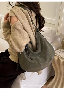 Détail du sac hobo vert olive mat avec coutures blanches et bandoulière sur un mannequin