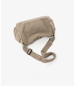 Flat lay of khaki canvas crossbody bag with adjustable strap and buckle closure