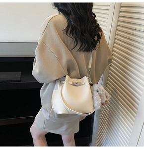 Detail of cream bucket bag with litchi texture leather and plush rabbit charm