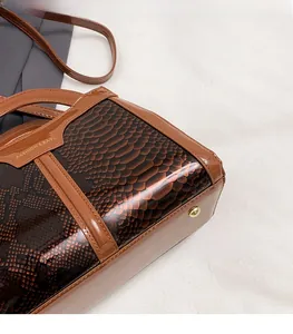 Detail of brown snakeskin texture and glossy patent leather on a mini crossbody bag