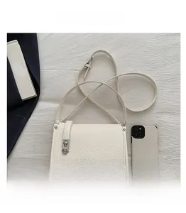 Detailed view of white lychee texture leather shoulder bag with silver buckle and adjustable strap