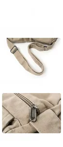 Detail view of the adjustable canvas strap and smooth metal zipper on a beige messenger bag