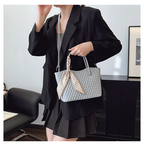Detail of light blue quilted handbag with checkered scarf and slim leather strap