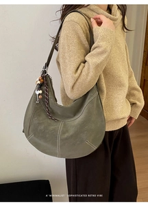 Détail du sac hobo vert olive avec surpiqûres et breloque ethnique en perles de bois