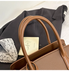 Détail du sac cabas en cuir marron vintage avec poignées renforcées et surpiqûres