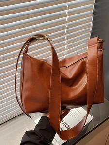 Vintage brown leather large tote bag with wide strap and gold hardware in soft lighting
