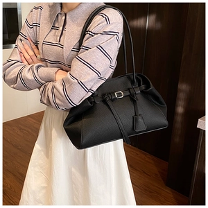 Detail view of black lychee grain leather tote bag with metal buckle and shoulder straps