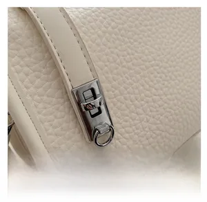 Close-up of silver twist lock and pebble grain leather texture on white baguette bag