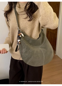 Détail d'un sac demi-lune vert foncé mat avec coutures blanches et breloque en perles
