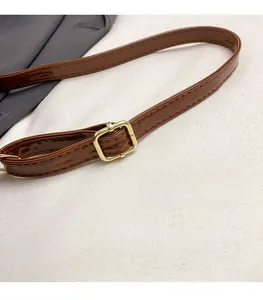 Detail of adjustable brown patent leather shoulder strap with a gold-tone metal buckle