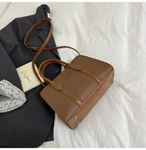 Vue détaillée du sac en cuir litchi marron avec pieds en métal argenté sur tissu blanc