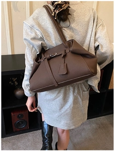 Model view of a large brown faux leather tote bag with stylish decorative strap and buckle