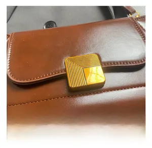 Makroaufnahme der goldenen Metallschnalle und feinen Nähte an der braunen Leder-Handtasche