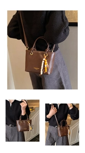 Detail view of brown leather bucket bag with fashion print and beaded charm accent