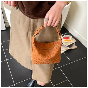 Close-up of woven leather texture on orange brown dumpling bag with top handle