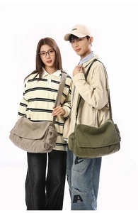 Detailed view of washed canvas messenger bags in army green and light grey on models