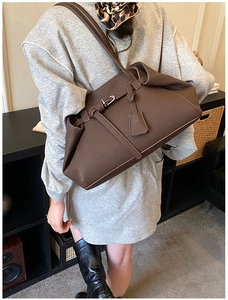 Detail of dark brown large tote bag showing lychee grain texture and metal buckle strap
