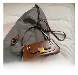 Details der braunen Baguette-Tasche mit goldener Wellenschnalle und Schultergurt