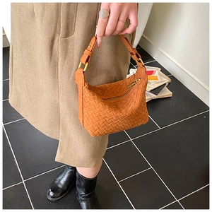 Detail of woven brown leather handbag with gold hardware and elegant stitching texture