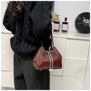 Detail of dark brown bucket bag with woven texture and pearl chain drawstring closure