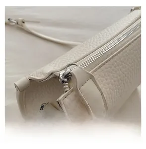 Detail view of smooth silver zipper and lychee pattern leather on beige handbag