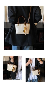 Detail of cream crossbody bucket bag with brown handles and colorful beaded charm