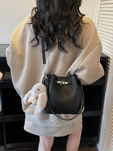 Litchi pattern black bucket bag with silver lock and rabbit pendant on a model
