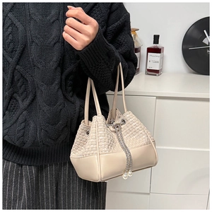 Detail of beige woven bucket bag featuring pearl drawstring and premium texture