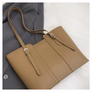 Macro shot of brown leather tote bag with lychee texture and silver buckle details