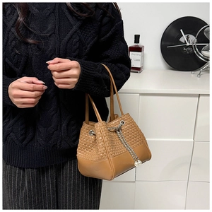 Close-up of woven bucket bag with chain drawstring and elegant pearl accents