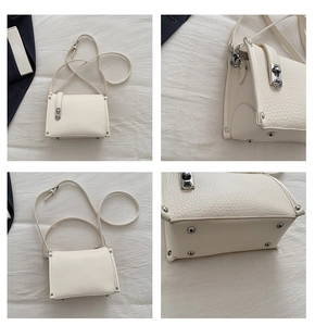 Detail view of cream leather handbag with silver twist lock and protective metal feet