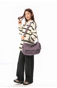 Detailed view of purple washed canvas messenger bag with wide shoulder strap and flap