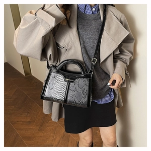 Detail of snake skin texture and black leather handle on the crossbody square bag