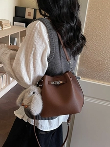 Brown litchi leather bucket bag with silver turn-lock and grey rabbit charm on strap