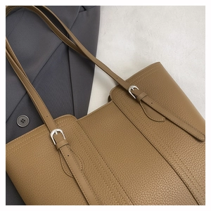 Detail of brown litchi pattern leather tote bag with silver buckle and adjustable strap