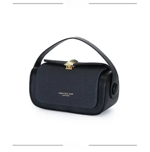 Detail of black cylinder handbag with carbon fiber texture and gold rectangular lock