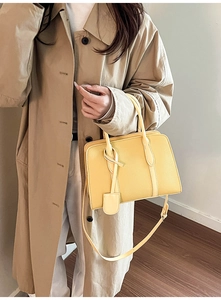 Détail du sac cabas jaune en cuir avec motif litchi et élégant pendentif décoratif