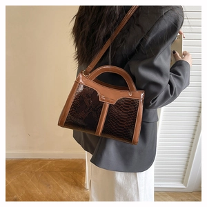 Detail of brown snakeskin texture and smooth leather finish on a small crossbody bag