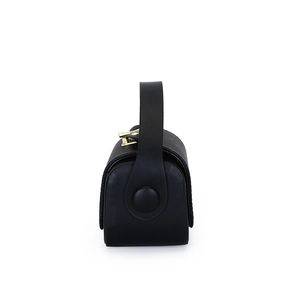 Detail of black pebbled leather texture and gold metal buckle on structured handbag